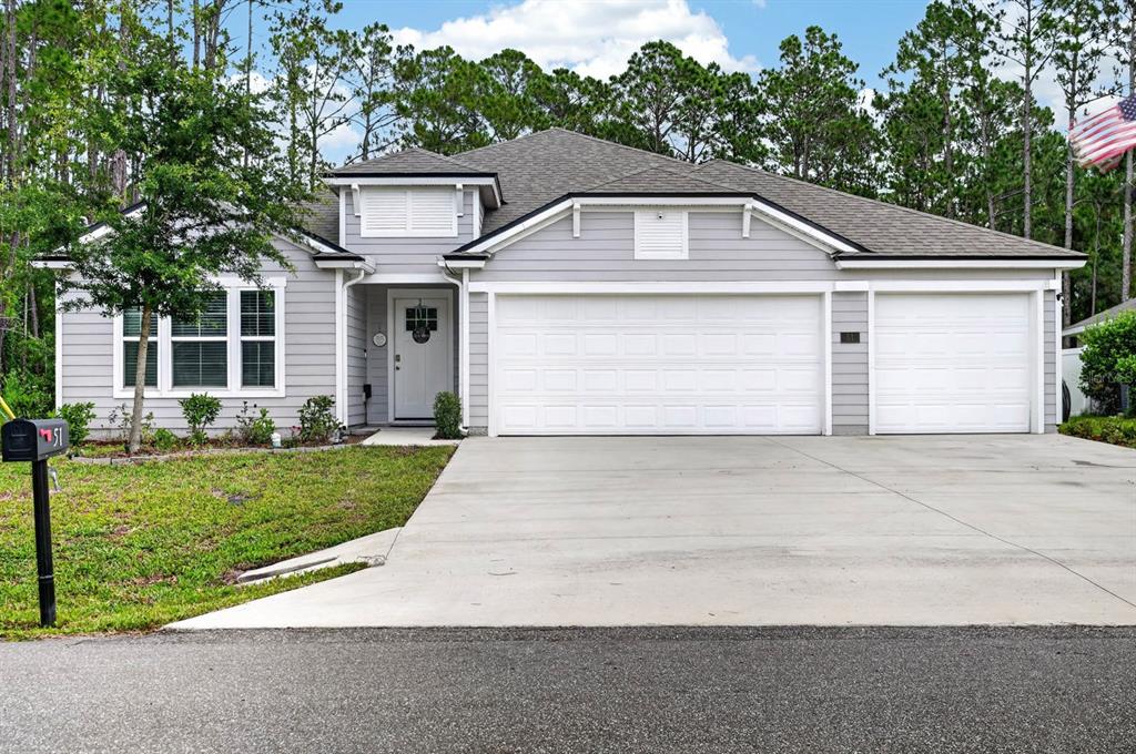 A single-story gray house with a three-car garage and a front yard — 51 SENTINEL TRAIL, PALM COAST, FL