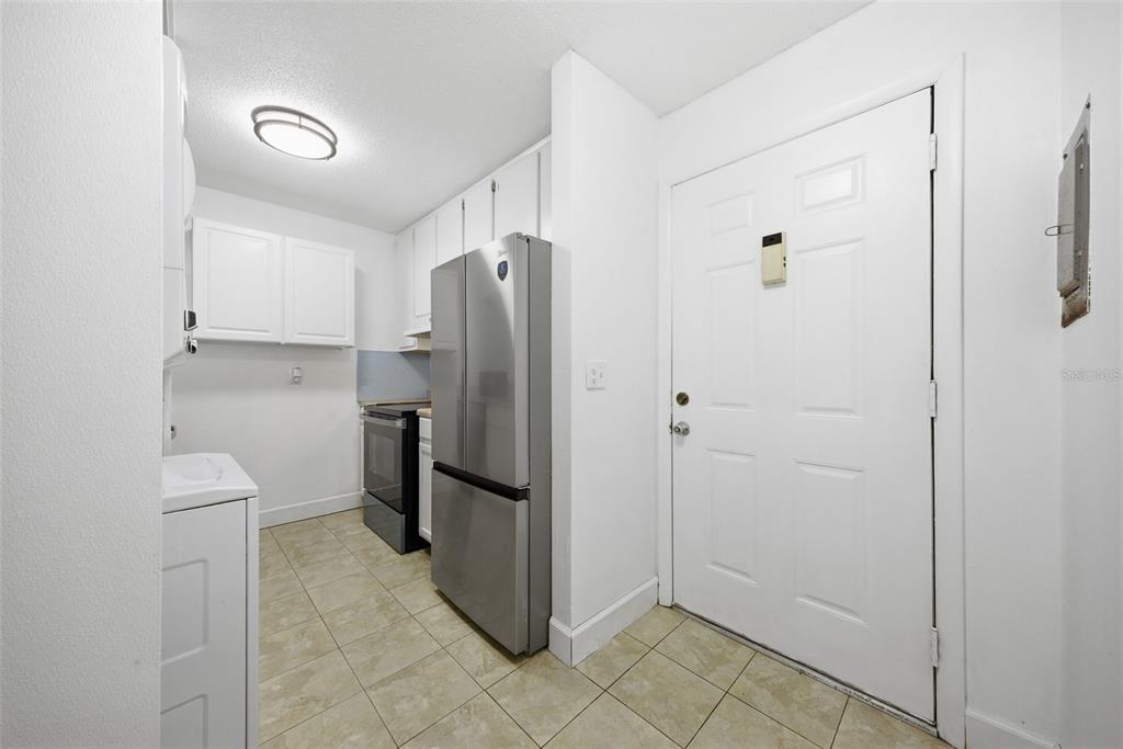 A small kitchen features white cabinets, stainless steel appliances, and light-colored tile flooring — 141 FERNERY ROAD UNIT A3, LAKELAND, FL