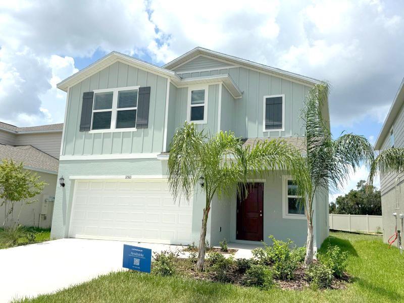 A two-story house with light green vertical siding, a white garage, and a palm tree — 11921 NOBLE CHASE PATH, DADE CITY, FL