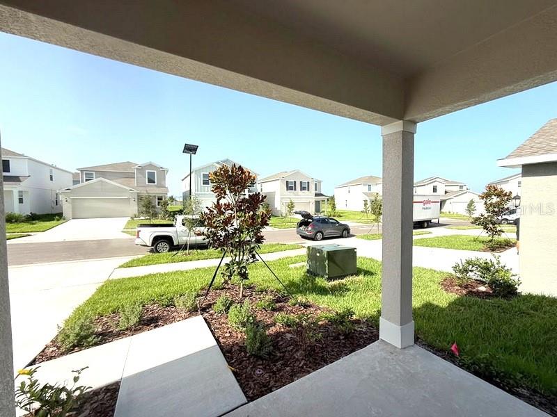 A view from a covered porch looking out at a suburban street with houses — 11921 NOBLE CHASE PATH, DADE CITY, FL