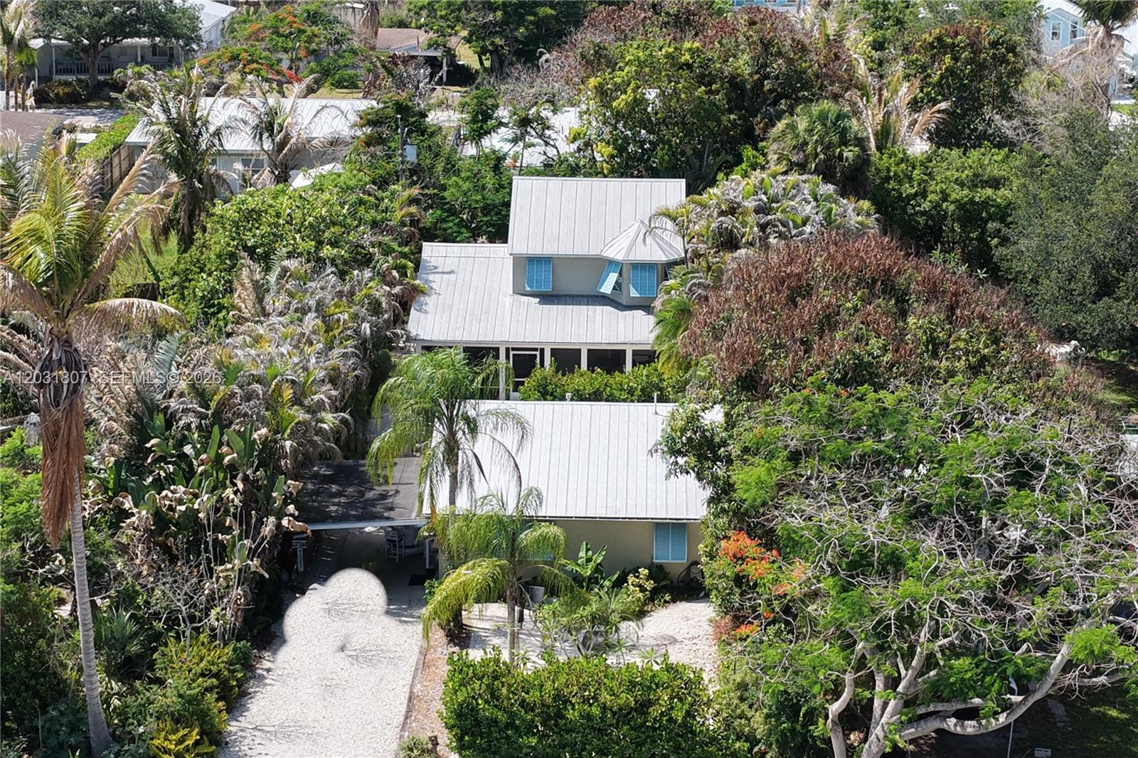 An aerial view shows two houses with metal roofs surrounded by lush tropical vegetation — 4225 SE Westfield St, Stuart FL 34997, STUART, FL