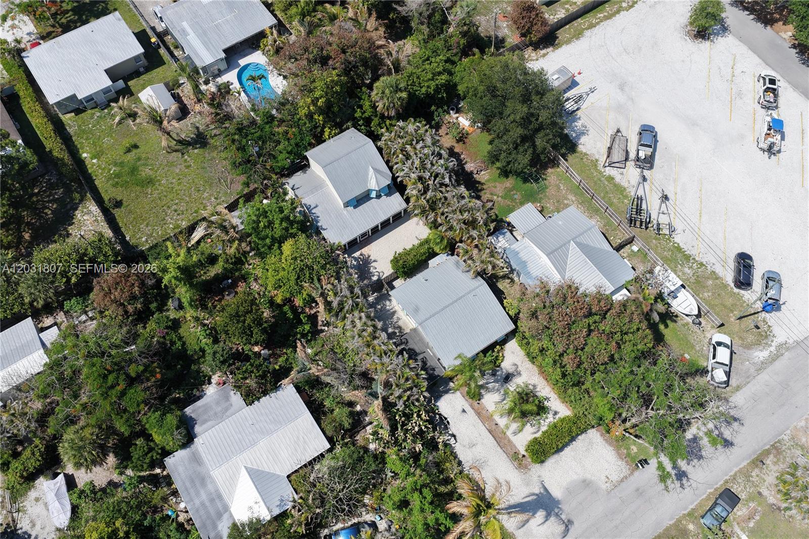 An aerial view shows several houses with metal roofs surrounded by trees and gravel lots — 4225 SE Westfield St, Stuart FL 34997, STUART, FL