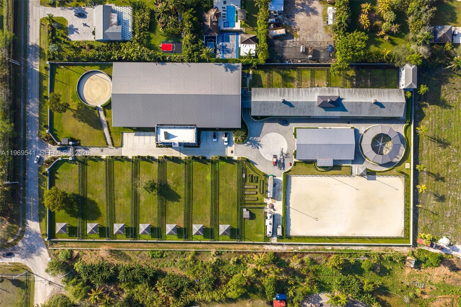 Aerial view of an equestrian property featuring a large indoor arena, stables, and riding paddocks — 2625 SW 148th Ave, Davie FL 33331, DAVIE, FL