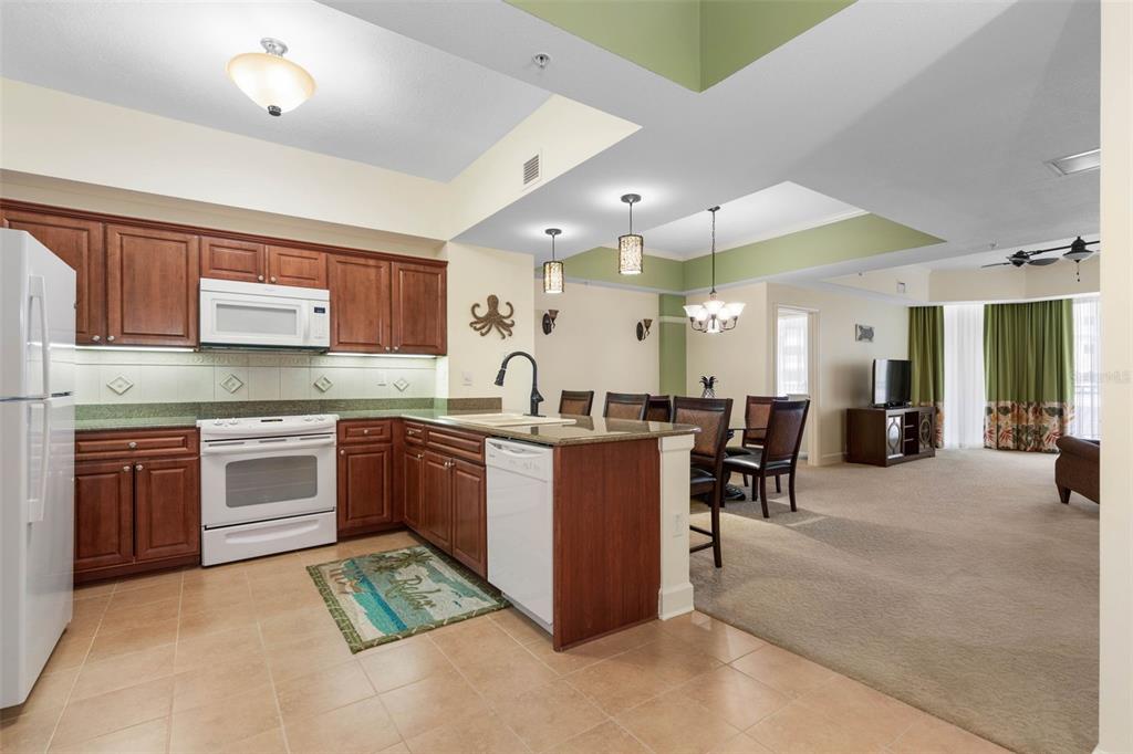 A kitchen with wooden cabinets and a dining area featuring a tray ceiling — 200 OCEAN CREST DRIVE UNIT 108, PALM COAST, FL