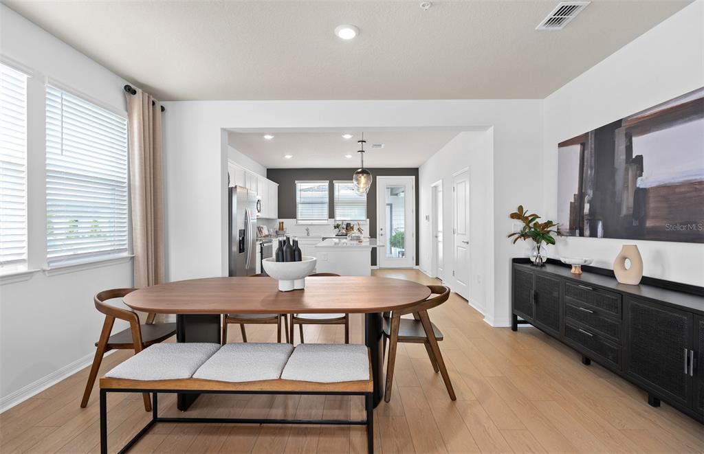 A dining room with a wooden table and bench opens into a modern kitchen — 6355 ARGENT WOOD DRIVE, WINTER GARDEN, FL