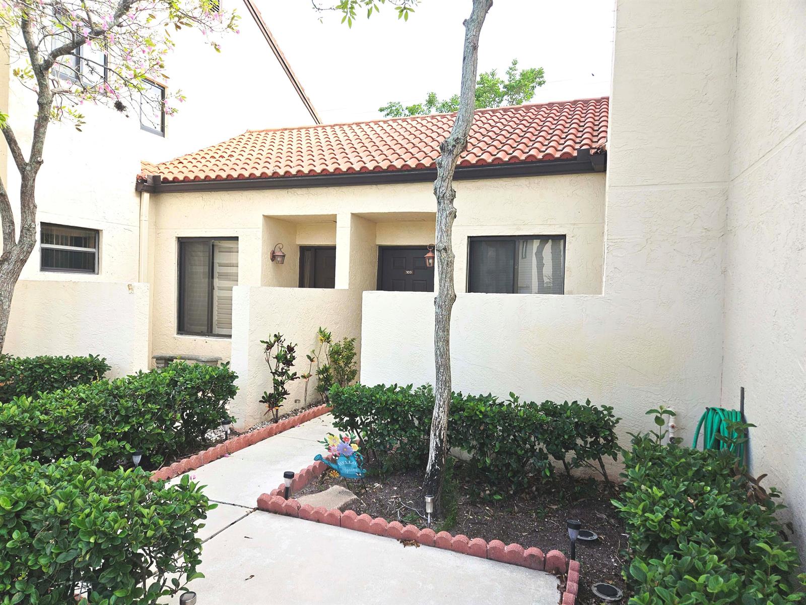 A walkway leads to the entrance of a stucco building with a tiled roof — 16 Vía De Casas Sur # 103, Boynton Beach FL 33426, BOYNTON BEACH, FL
