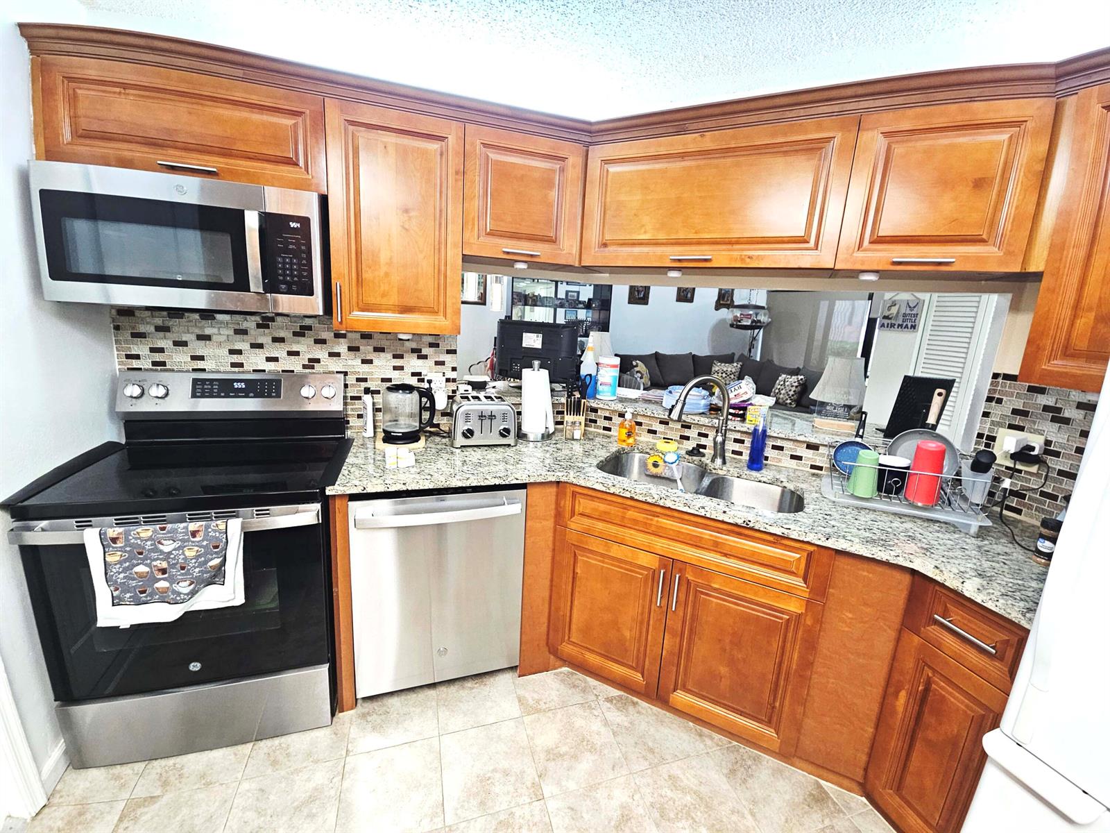 A kitchen with wood cabinets, stainless steel appliances, granite countertops, and a tile backsplash — 16 Vía De Casas Sur # 103, Boynton Beach FL 33426, BOYNTON BEACH, FL