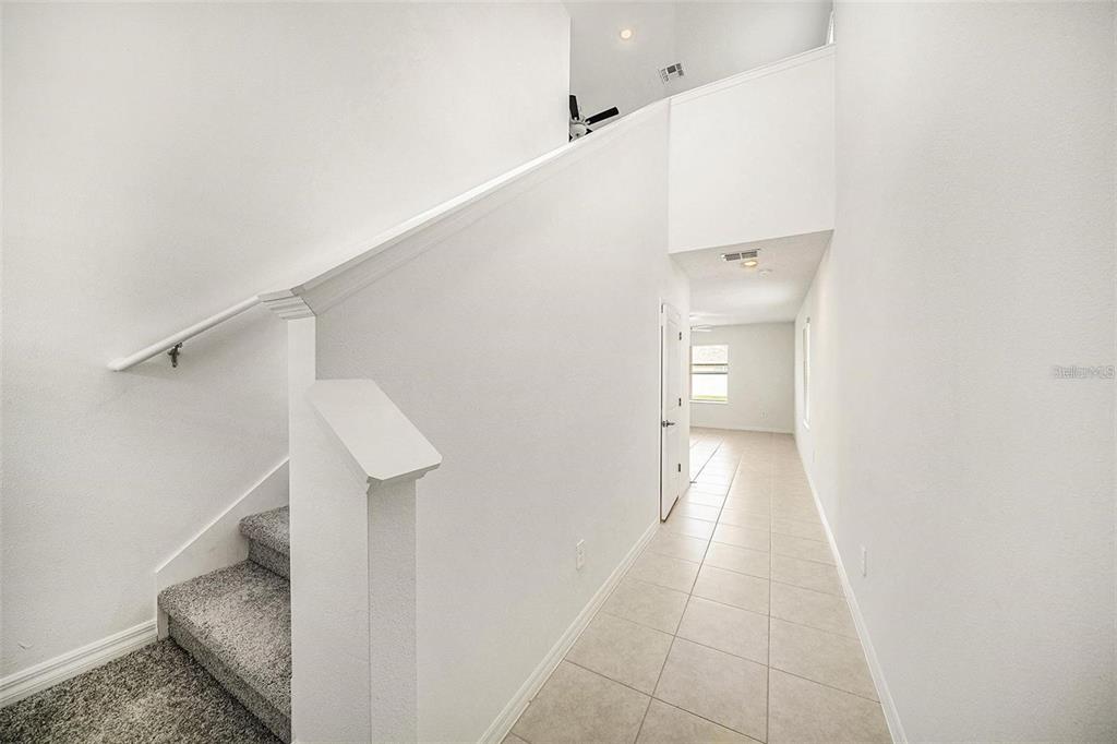A view of a tiled hallway with a carpeted staircase and a high ceiling — 2871 SILVER SCALLOP LOOP, WIMAUMA, FL