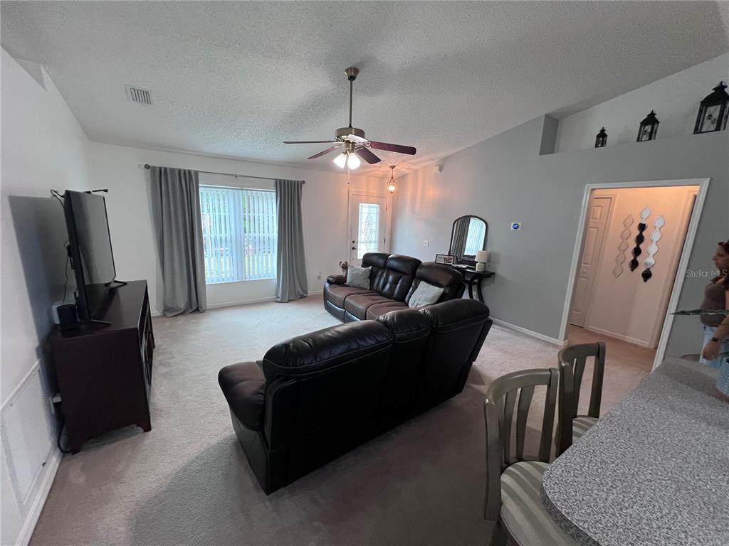 A living room features a dark leather sectional, a television console, and a ceiling fan — 632 N GOODRICH DRIVE, DELTONA, FL