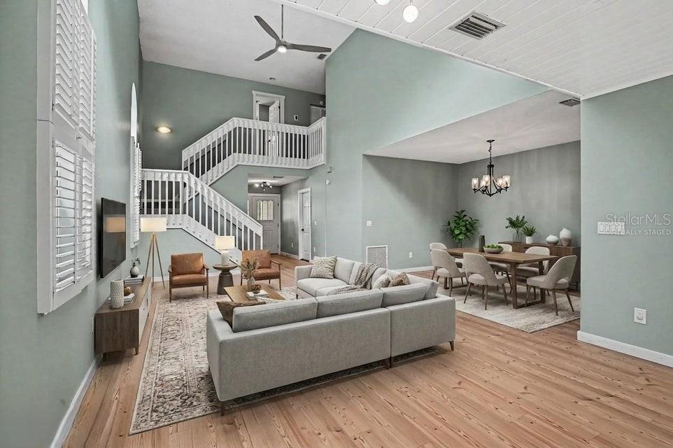 A living and dining area with high ceilings, light wood floors, and a central staircase — 34 BRISTOL DRIVE, PALM COAST, FL