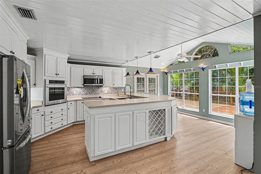 A bright kitchen features white cabinets, a large island with wine storage, and vaulted ceilings — 34 BRISTOL DRIVE, PALM COAST, FL