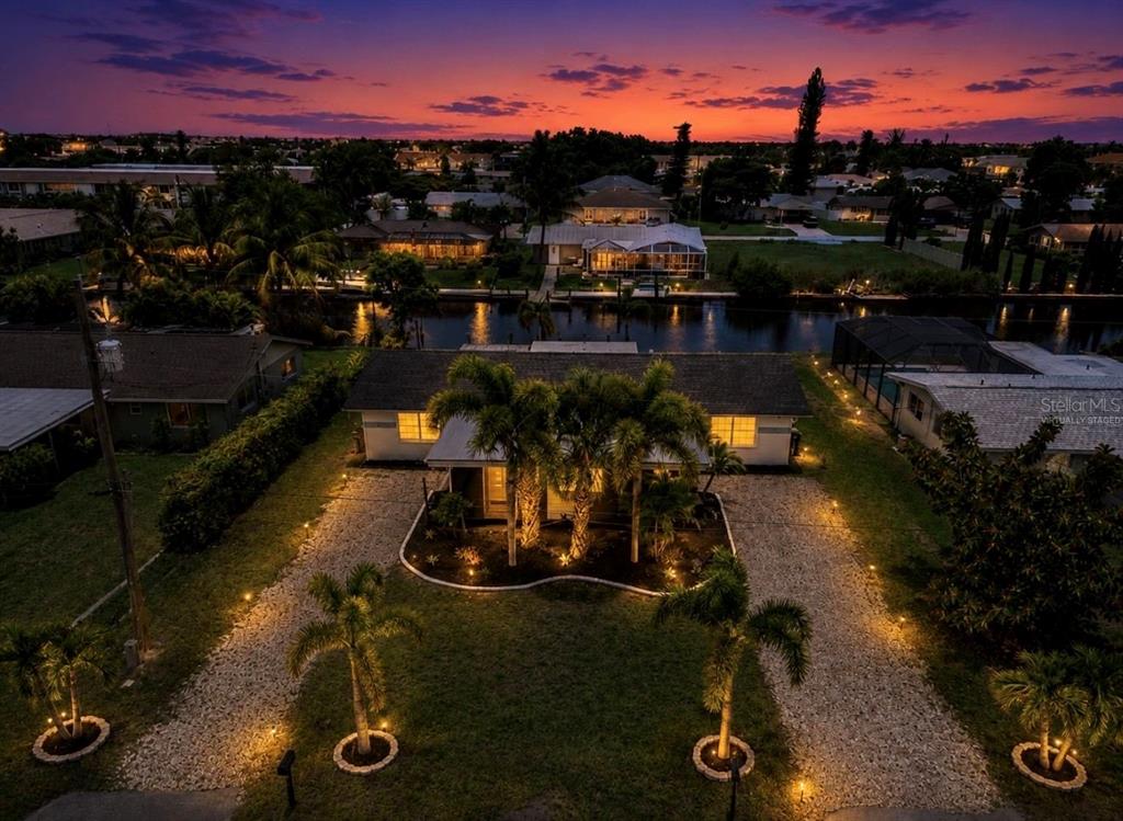 An aerial view of a house at dusk with a gravel driveway and palm trees — 4933 VICTORIA DRIVE, CAPE CORAL, FL