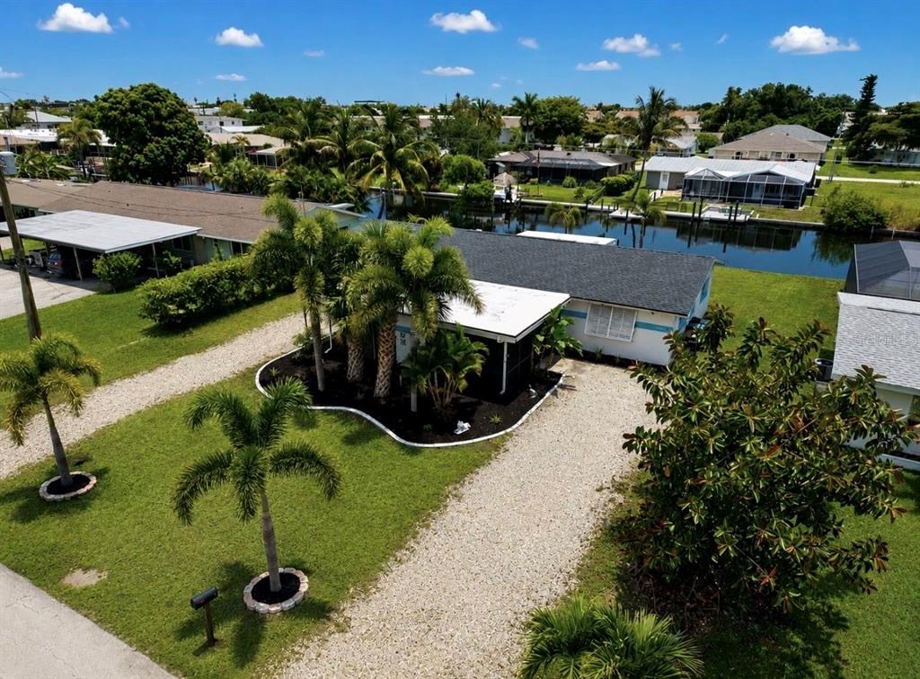 An aerial view of a single-story house with a gravel driveway and a canal behind — 4933 VICTORIA DRIVE, CAPE CORAL, FL