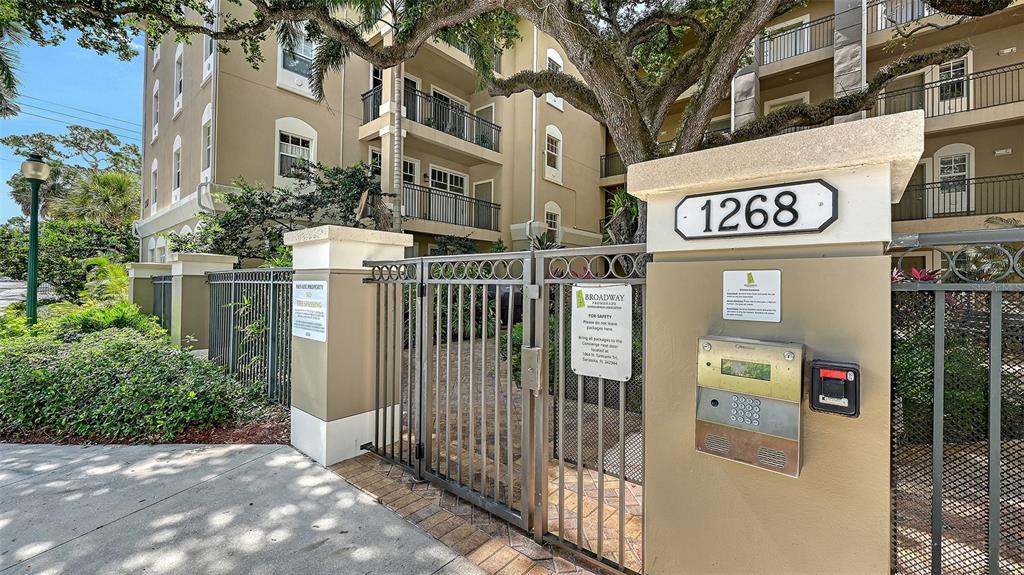 A gated entrance with a keypad and address sign leads to a multi-story apartment building — 1268 11TH STREET UNIT 2404, SARASOTA, FL