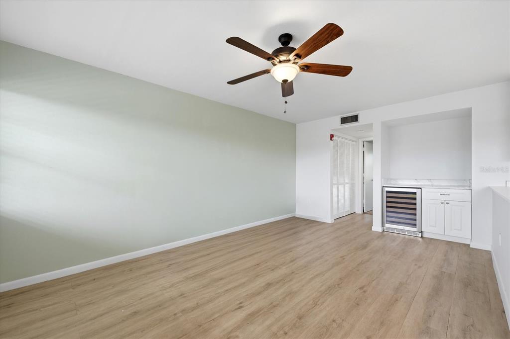 A room with light wood flooring, a ceiling fan, and a built-in wine refrigerator — 1001 77TH AVENUE N UNIT 307, ST PETERSBURG, FL