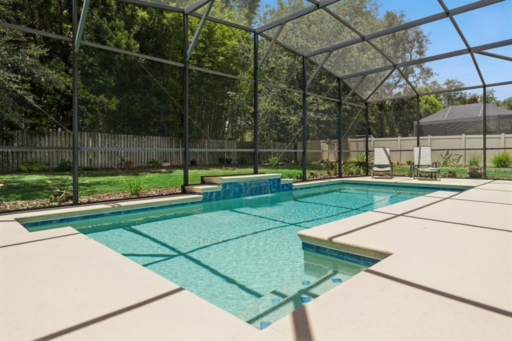 A screened-in swimming pool with a water feature and a concrete deck in a backyard — 3169 PINENUT DRIVE, APOPKA, FL