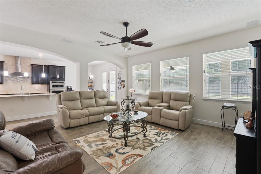 A living room with light-colored tile floors, a patterned rug, and two beige reclining sofas — 3169 PINENUT DRIVE, APOPKA, FL