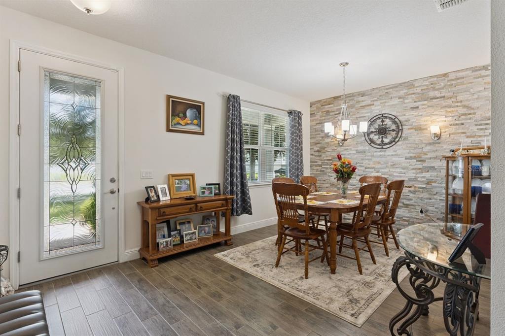 A dining room features a stone accent wall, a wooden table with chairs, and tile flooring — 3169 PINENUT DRIVE, APOPKA, FL