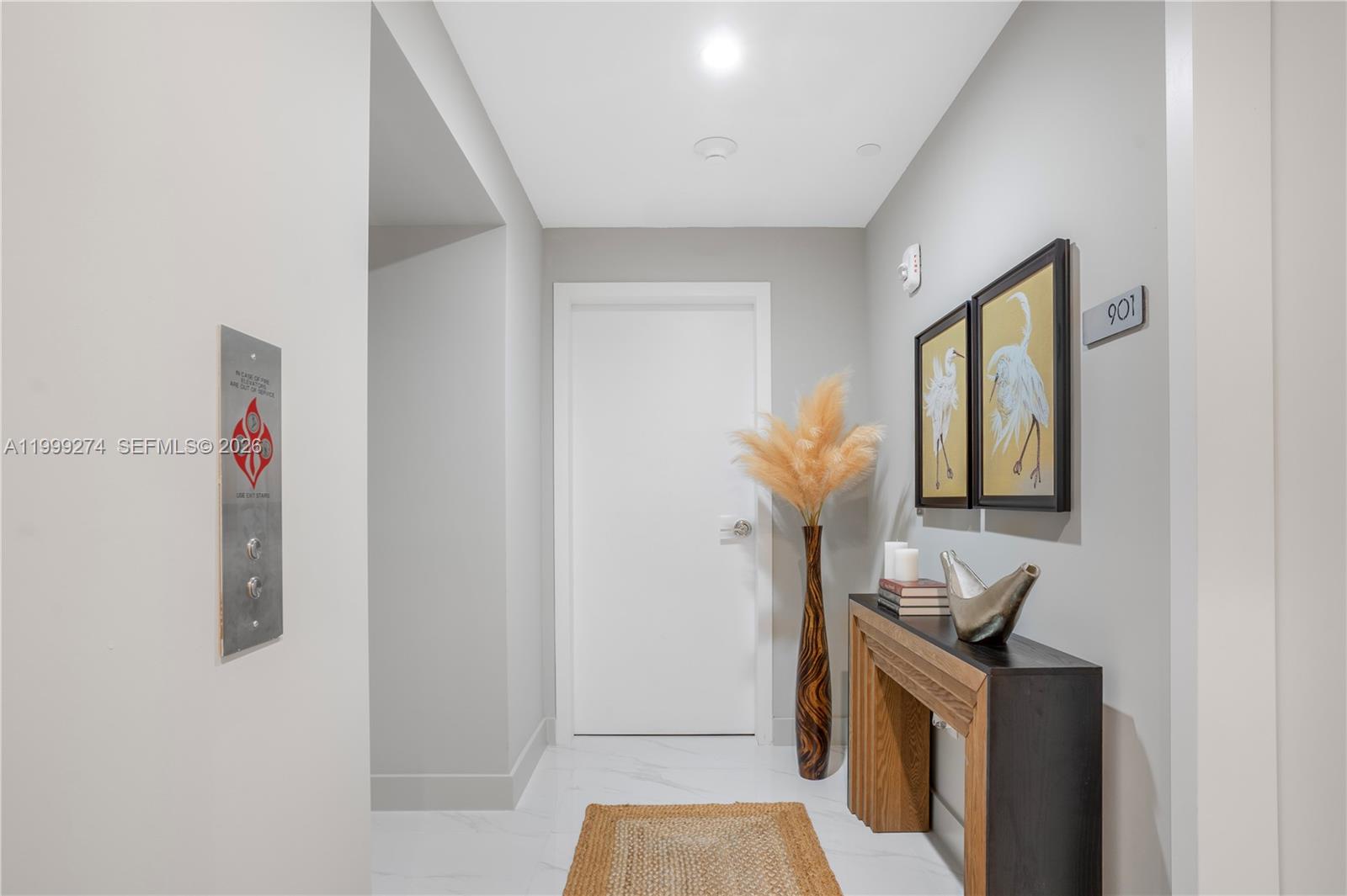 A hallway features a white door, a console table, two bird paintings, and marble flooring — 700 NE 24 # 901, Miami FL 33137, MIAMI, FL