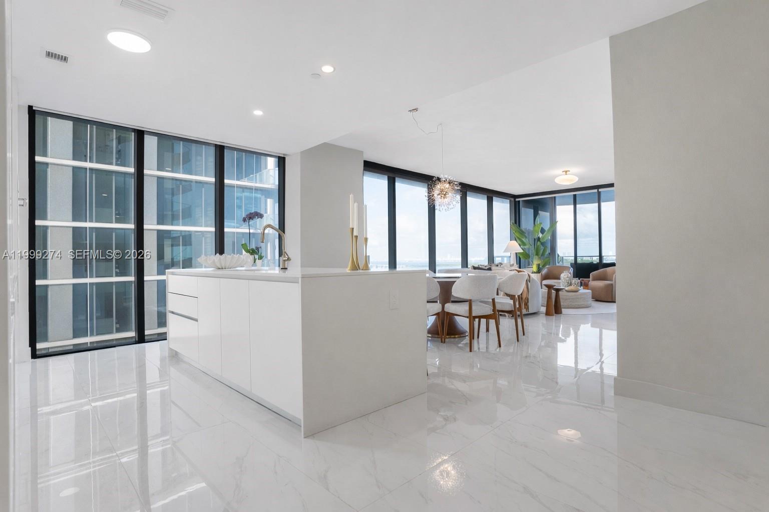 A modern kitchen island with white cabinets sits in an open-concept room with marble floors — 700 NE 24 # 901, Miami FL 33137, MIAMI, FL