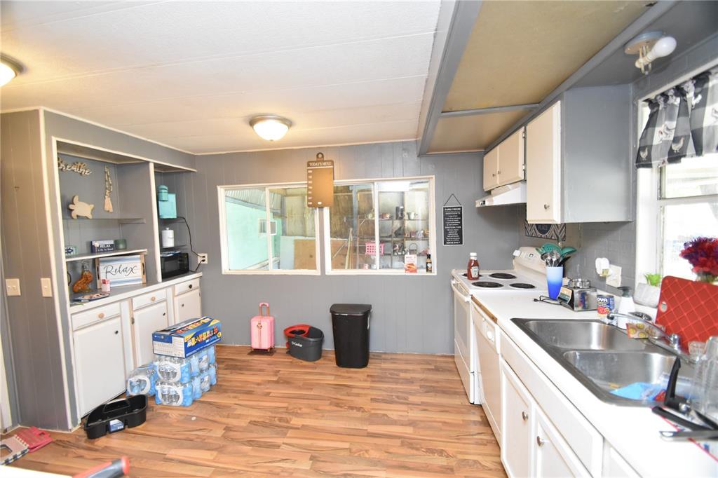 A kitchen with white cabinets, gray walls, wood-look flooring, and a window overlooking a porch — 5722 LITTLE EVA ROAD, HAINES CITY, FL