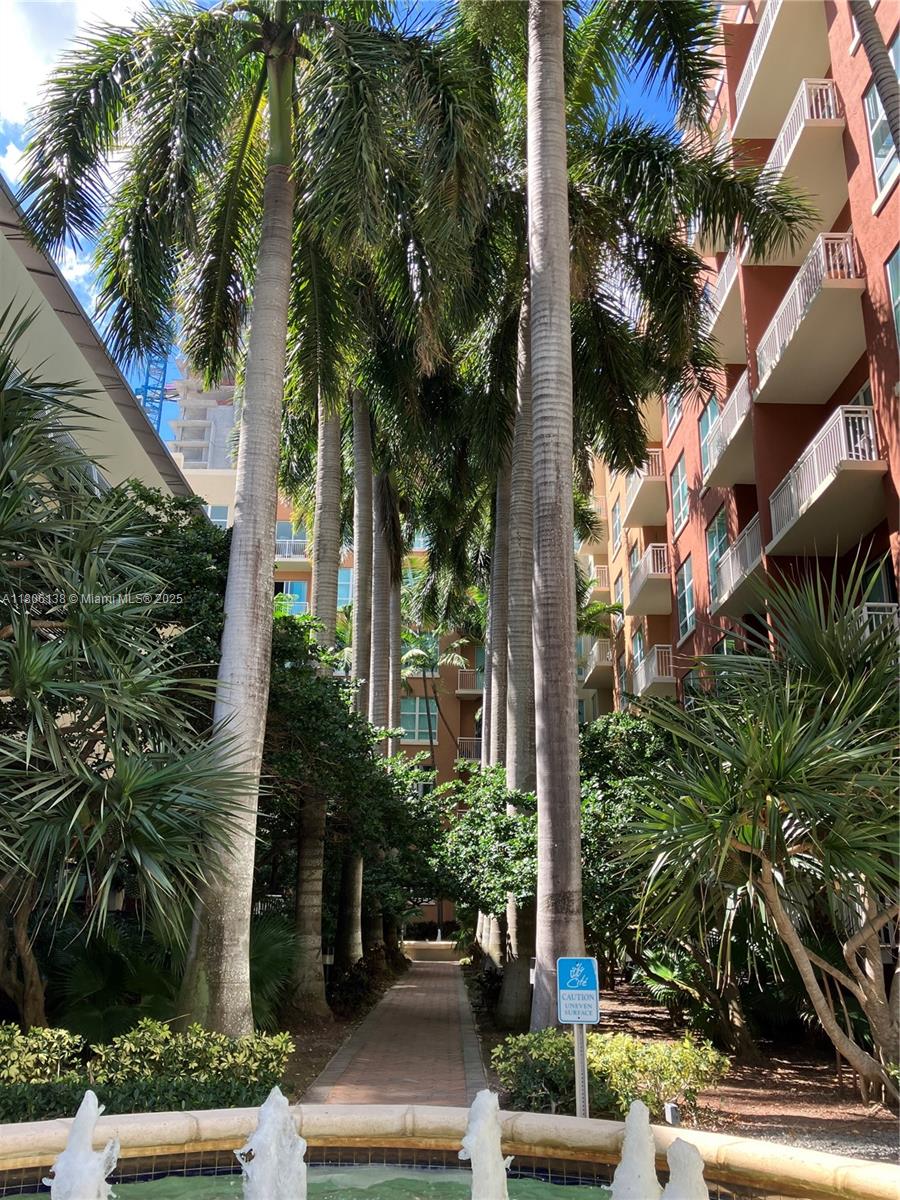 A brick pathway leads between tall palm trees and apartment buildings toward a small fountain — 2001 Biscayne Blvd # 3503, Miami FL 33137, MIAMI, FL