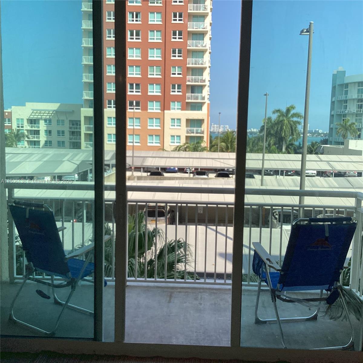 A balcony with two blue folding chairs overlooks a parking lot and nearby apartment buildings — 2001 Biscayne Blvd # 3503, Miami FL 33137, MIAMI, FL