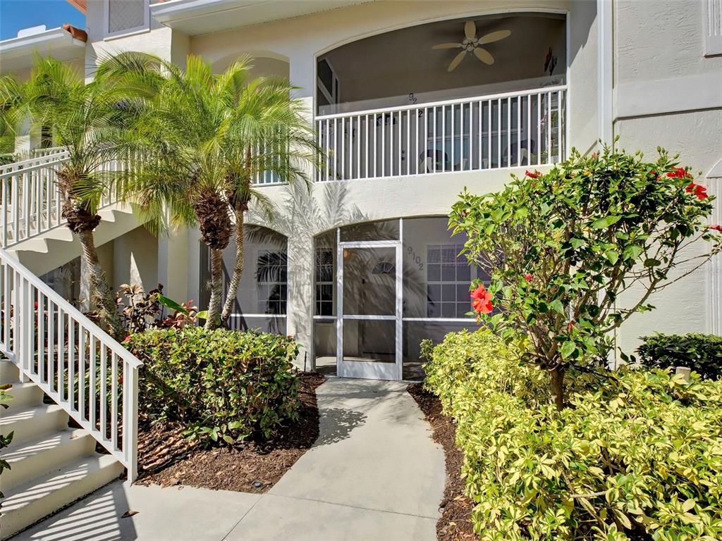 A two-story building exterior features a ground-level screened entryway and an upper-level balcony — 9102 L PAVIA BOULEVARD UNIT 9102, VENICE, FL