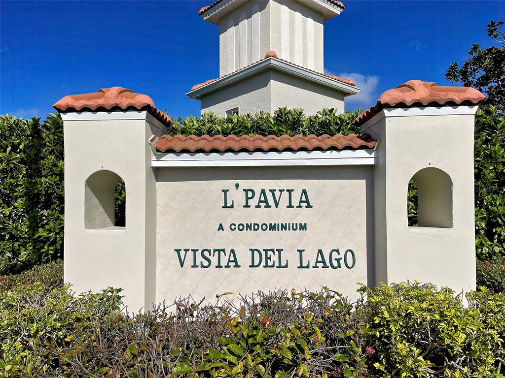 A stucco monument sign for L'Pavia at Vista Del Lago stands before a blue sky — 9102 L PAVIA BOULEVARD UNIT 9102, VENICE, FL