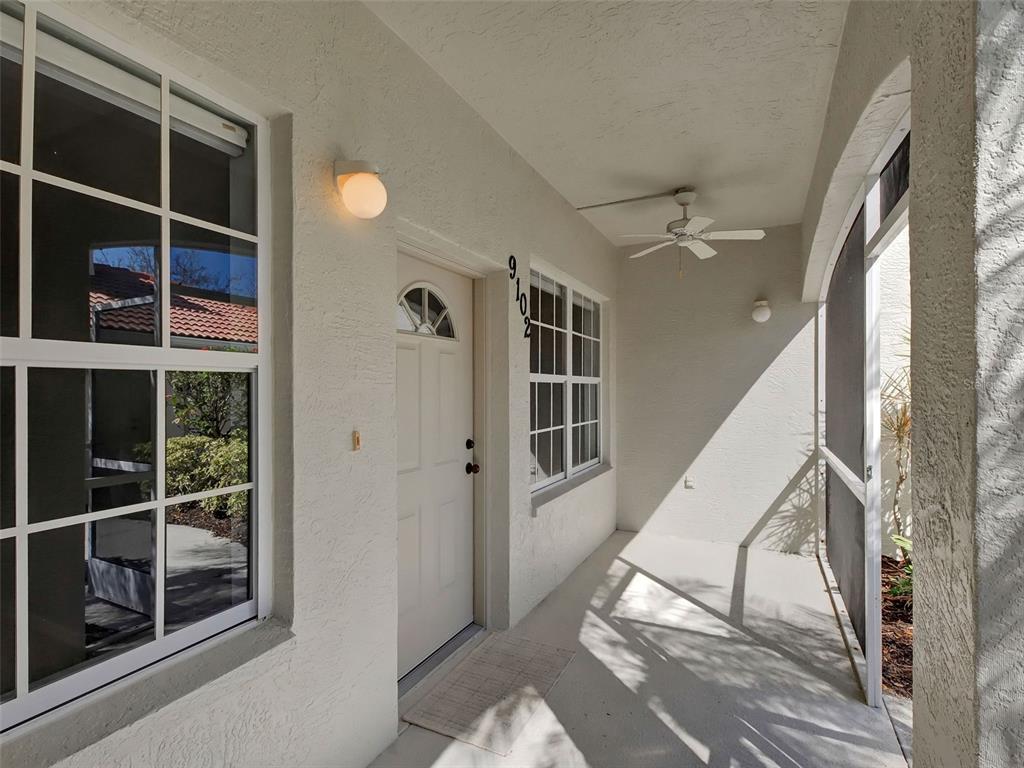 A covered entryway features a white front door, a ceiling fan, and a screened enclosure — 9102 L PAVIA BOULEVARD UNIT 9102, VENICE, FL
