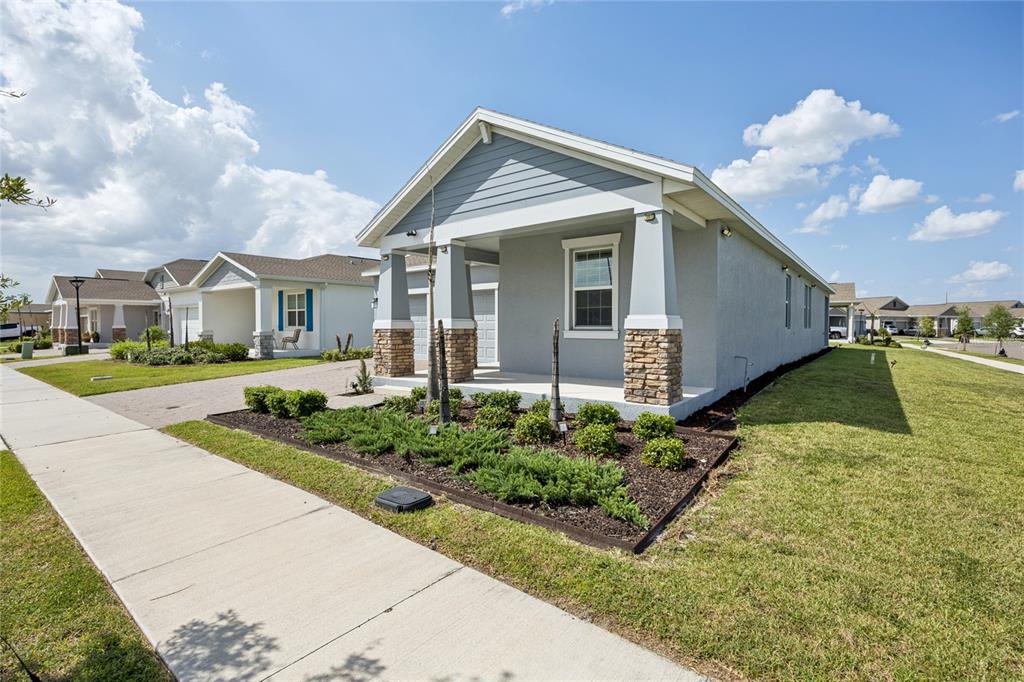 A single-story house with a gray exterior, stone-accented porch columns, and a landscaped front yard — 2466 RELAXING LANE, KISSIMMEE, FL