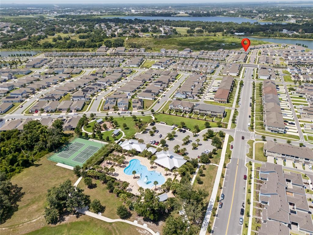 This aerial view shows a residential neighborhood with a community pool, tennis courts, and roads — 2466 RELAXING LANE, KISSIMMEE, FL