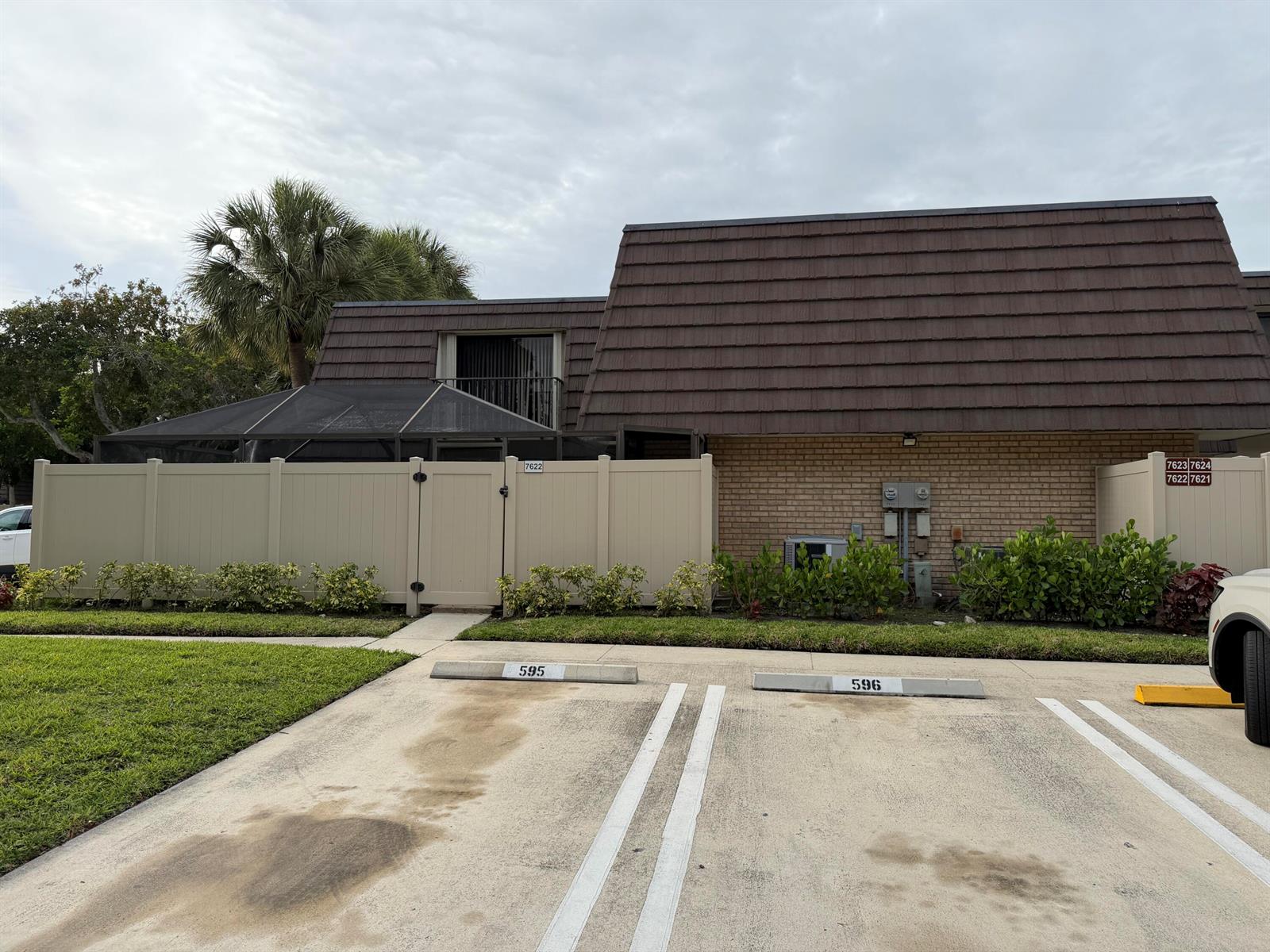 A tan vinyl fence encloses a patio area in front of a brick building — 7622 N 76th Way # 200, West Palm Beach FL 33407, WEST PALM BEACH, FL