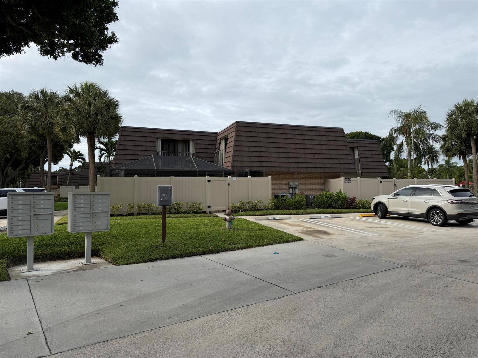 A two-story building with a mansard roof stands behind a fence near a parking lot — 7622 N 76th Way # 200, West Palm Beach FL 33407, WEST PALM BEACH, FL
