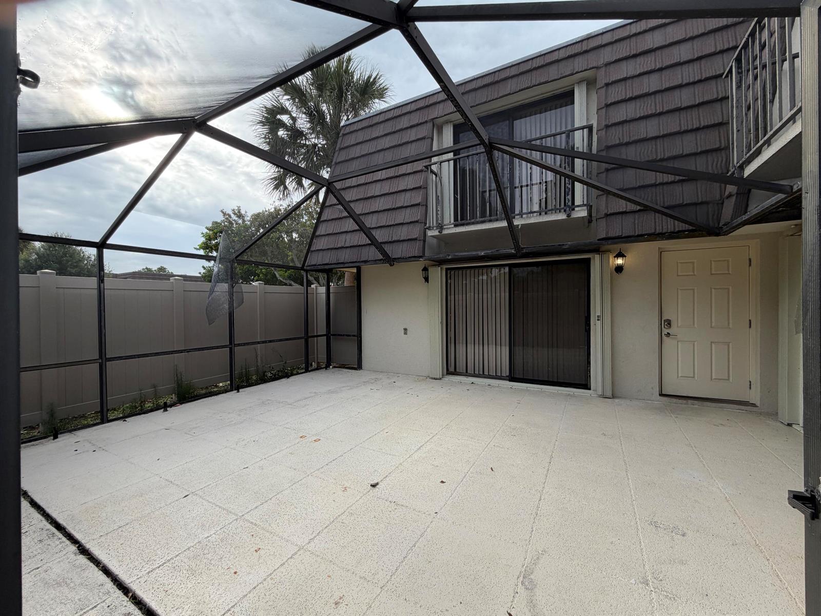 A screened-in patio with concrete flooring, a sliding glass door, and an exterior door — 7622 N 76th Way # 200, West Palm Beach FL 33407, WEST PALM BEACH, FL