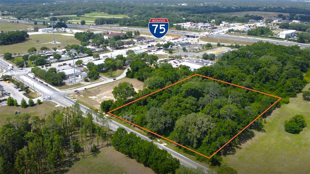 An aerial view shows a wooded, rectangular plot of land outlined in orange near a highway — 13350 SW 16TH AVENUE, OCALA, FL