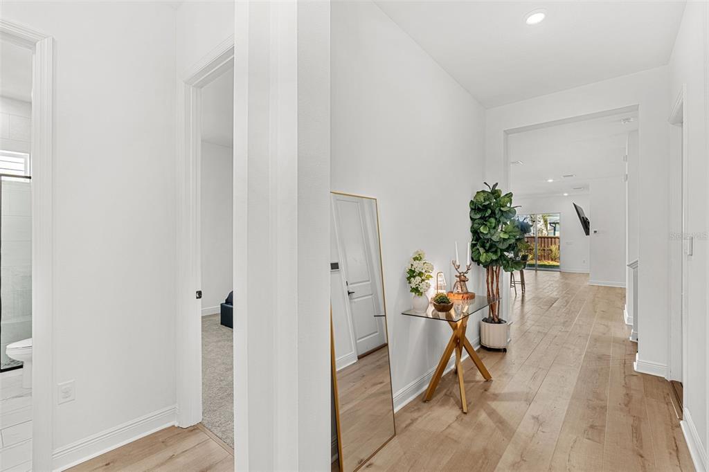 A bright hallway features light wood flooring, a glass console table, and a floor mirror — 3085 EXPEDITION DRIVE, ST CLOUD, FL