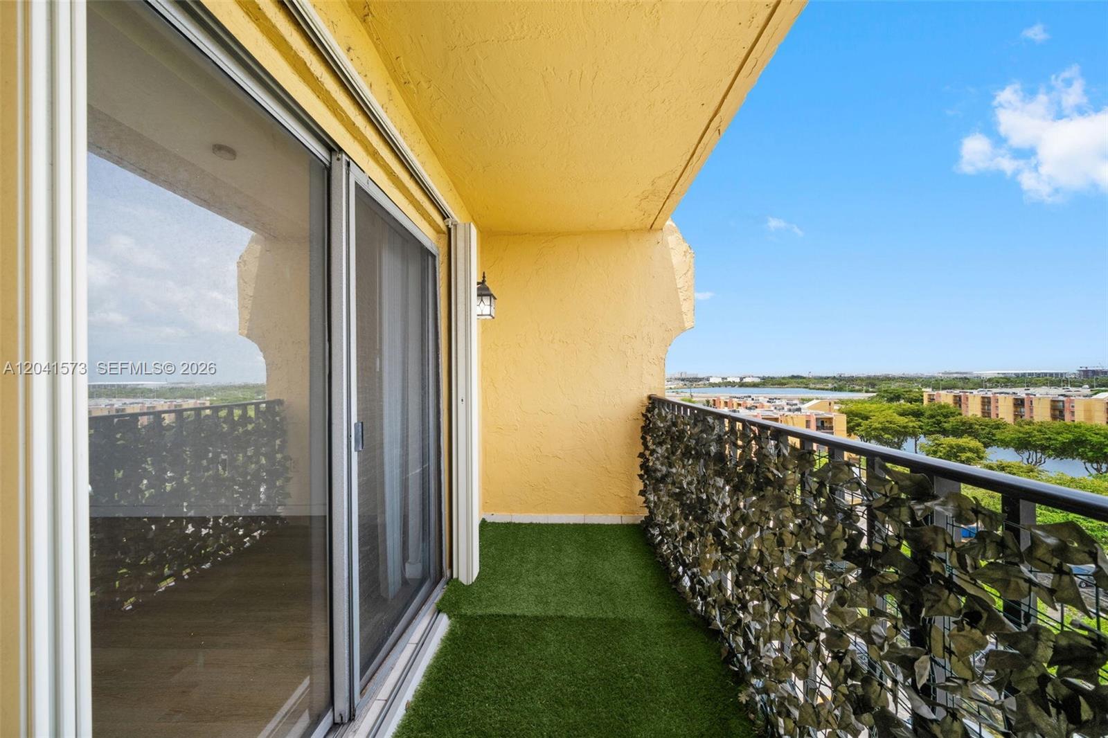 A balcony features artificial grass flooring, a privacy screen on the railing, and sliding doors — 4801 NW 7th St # 16, Miami FL 33126, MIAMI, FL