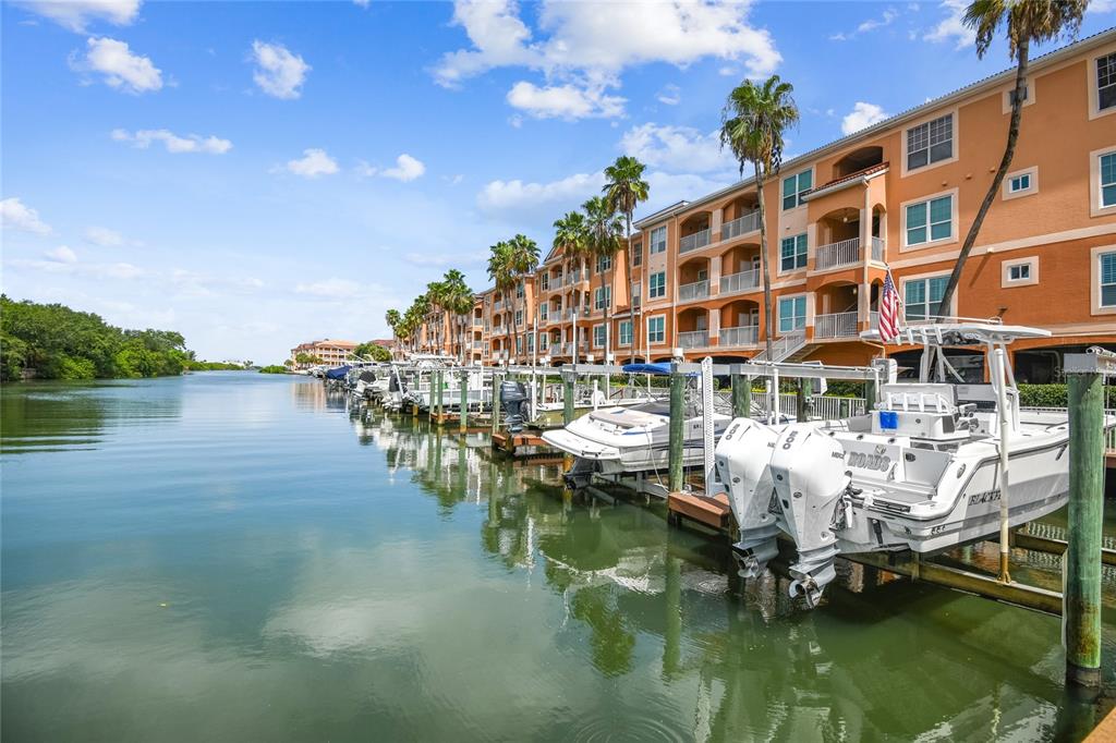 A row of boats is docked along a canal next to a multi-story apartment building — 5000 CULBREATH KEY WAY UNIT 1-312, TAMPA, FL