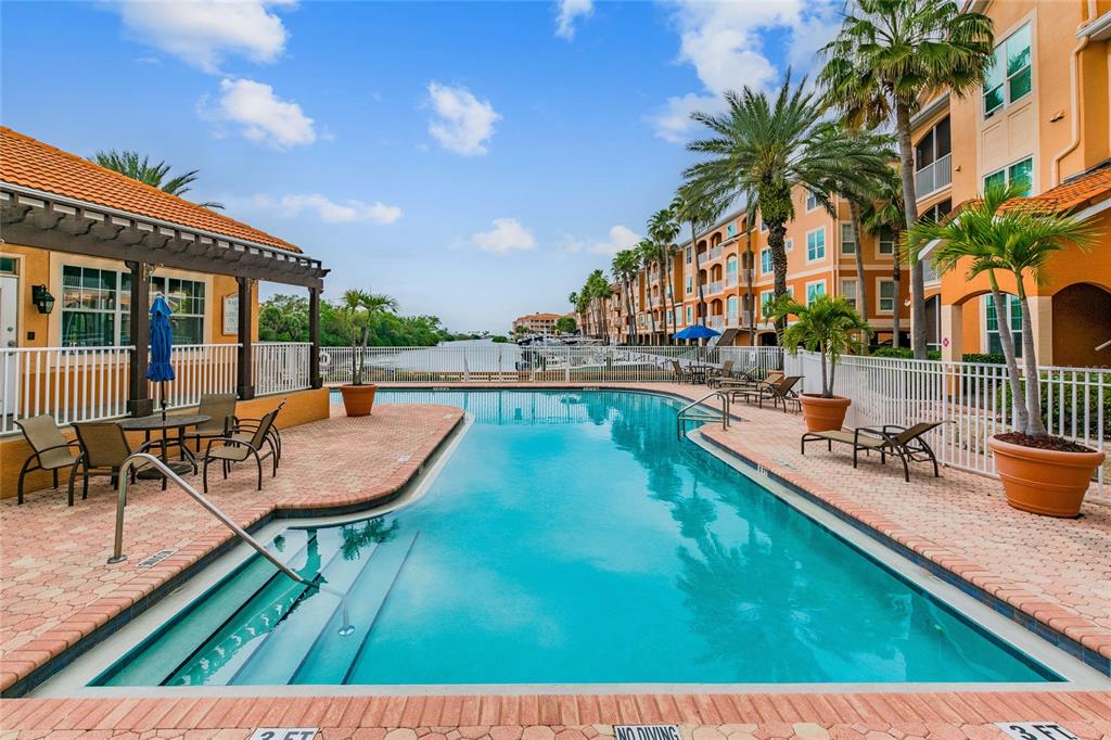 An outdoor swimming pool with a brick deck sits beside a multi-story apartment building — 5000 CULBREATH KEY WAY UNIT 1-312, TAMPA, FL