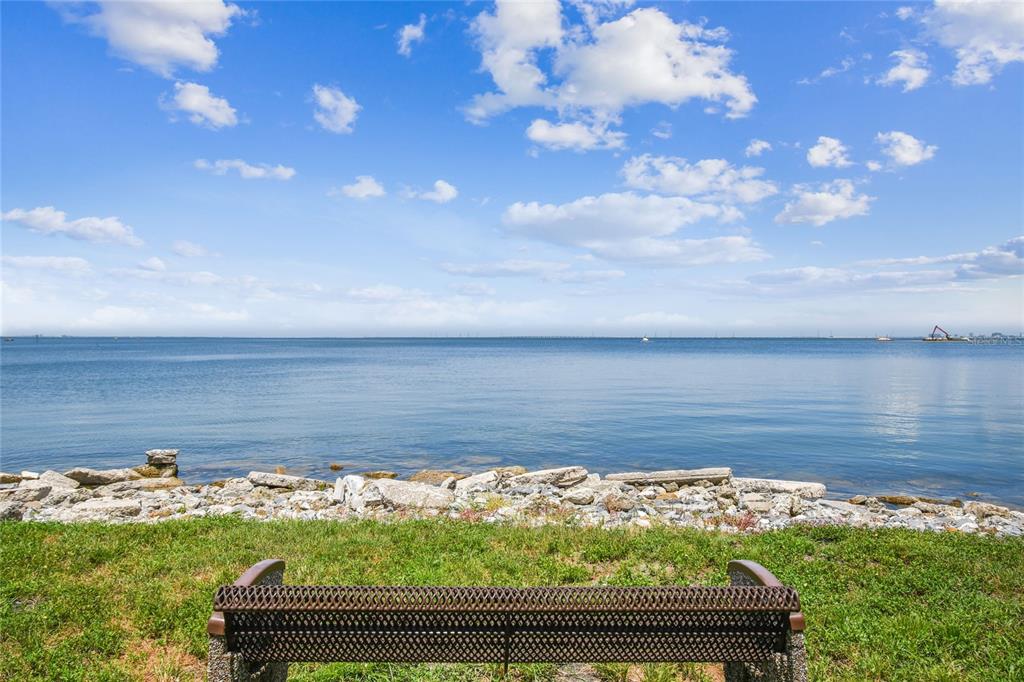 A metal bench sits on a grassy lawn overlooking a rocky shoreline and the ocean — 5000 CULBREATH KEY WAY UNIT 1-312, TAMPA, FL