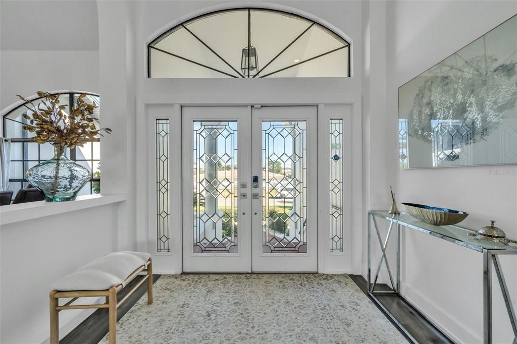 A bright entryway features double glass-paneled doors, a large arched transom window, and a console table — 112 LEEWARD ISLAND, CLEARWATER, FL