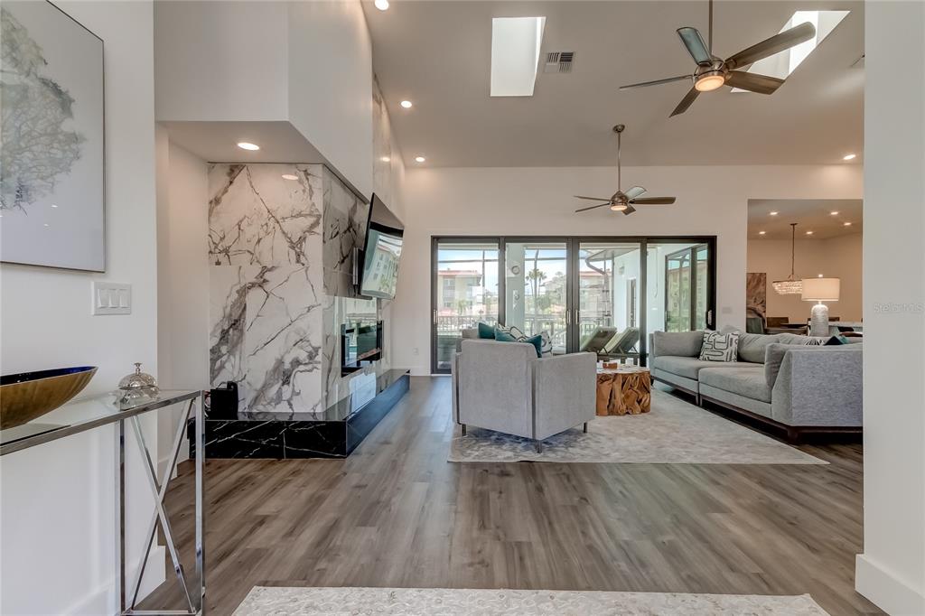 A living room features a marble fireplace, wood-look flooring, and sliding glass doors to a patio — 112 LEEWARD ISLAND, CLEARWATER, FL