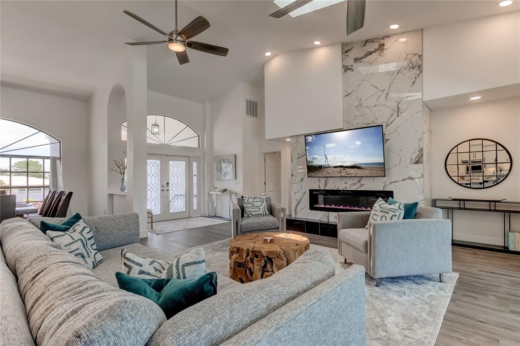 A living room features a marble fireplace, a large sectional sofa, and a ceiling fan — 112 LEEWARD ISLAND, CLEARWATER, FL