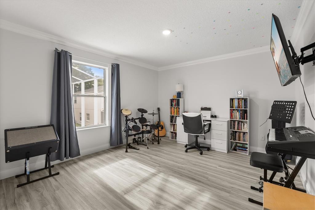 A music room with light wood-look flooring, a desk, bookshelves, a drum kit, and keyboard — 1792 GLENHAVEN CIRCLE, OCOEE, FL