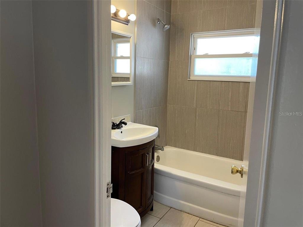 A bathroom features a vanity, a bathtub with a showerhead, and tiled walls — 320 W GRAVES AVENUE, ORANGE CITY, FL