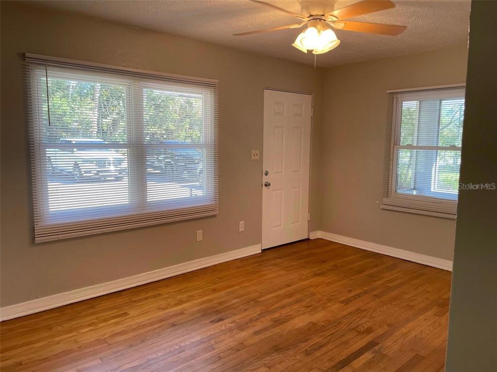 An empty room features hardwood floors, light-colored walls, a ceiling fan, and two windows — 320 W GRAVES AVENUE, ORANGE CITY, FL