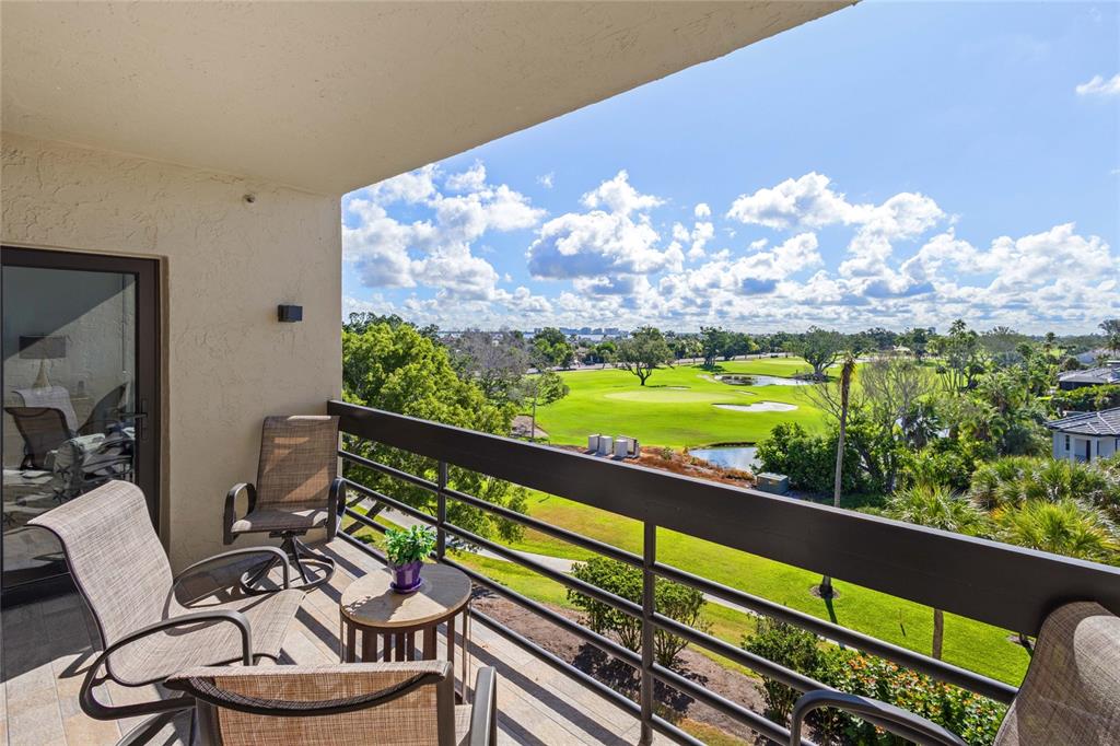 A balcony with patio furniture overlooks a green golf course under a blue sky — 1065 GULF OF MEXICO DRIVE UNIT 402, LONGBOAT KEY, FL