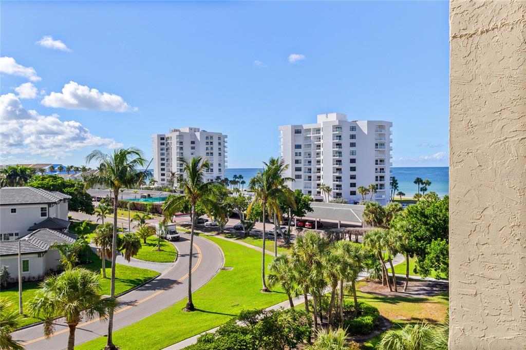 An elevated view of a coastal neighborhood with palm trees, a road, and two apartment buildings — 1065 GULF OF MEXICO DRIVE UNIT 402, LONGBOAT KEY, FL