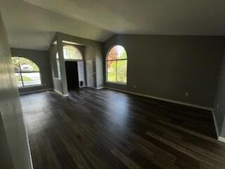 An empty living room features dark wood-look flooring, gray walls, and two arched windows — 108 Greentree Lane, FL 34797, FL